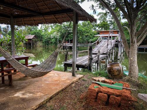 a resort with a hammock and a table and water at Numpu Baandin in Sam Roi Yot