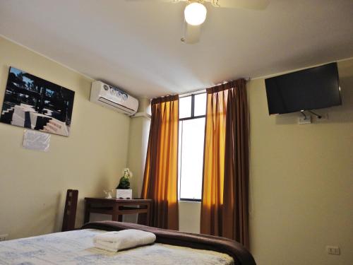 a bedroom with a bed and a window with a television at Hotel Torontel in Ica