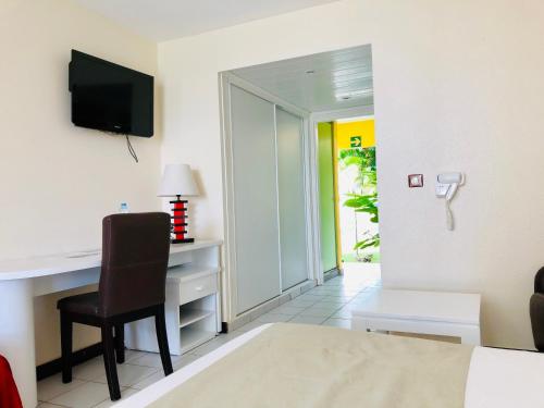 a hotel room with a desk and a chair at Canella Beach Hotel in Le Gosier