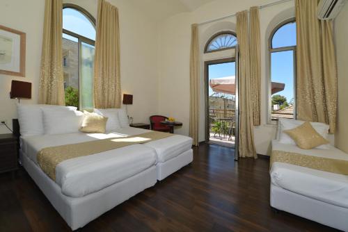 a bedroom with a large white bed and two windows at The Little House In Bakah in Jerusalem