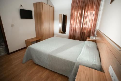 a bedroom with a white bed and wooden floors at Hotel Padre Cruz in Valença