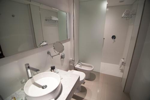 a bathroom with a sink and a toilet and a mirror at Salto Hotel y Casino in Salto