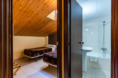 baño con 2 camas, bañera y lavamanos en Apartamentos Turisticos Poblado, en Arinsal