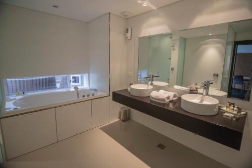 a bathroom with two sinks and a tub and a mirror at Salto Hotel y Casino in Salto
