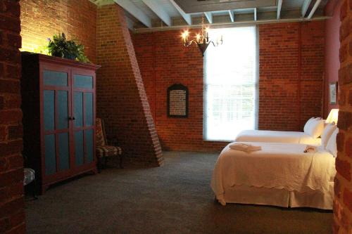 a brick room with a bed and a window at The Historic Brookstown Inn, Trademark Collection by Wyndham in Winston-Salem