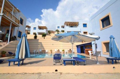 a pool with chairs and umbrellas next to a house at Gaitani Village in Léntas