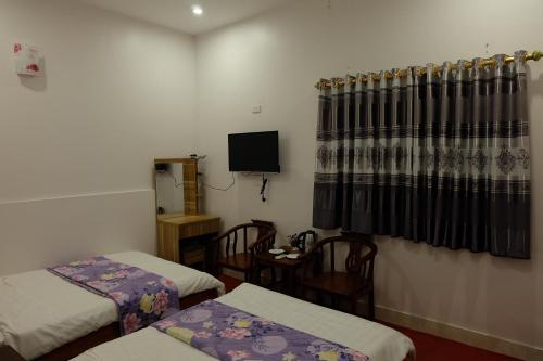 a small room with two beds and a tv at Tuan Tu Hotel in Dong Anh
