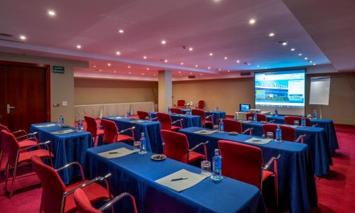 a conference room with blue tables and chairs and a screen at Hotel Attica21 Las Rozas in Las Rozas de Madrid