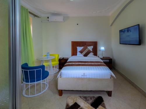 a bedroom with a bed and two chairs and a table at Jarin Hotel in Kampala