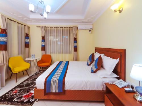 Una habitación de hotel con una cama, un escritorio y sillas. en Jarin Hotel, en Kampala