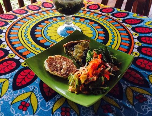 a green plate of food on a table with a drink at Samai Lodge Holistic Living in Olón