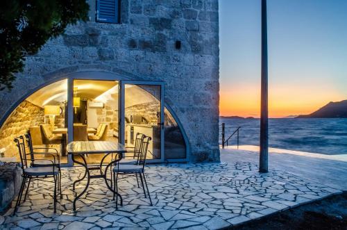 a dining table and chairs on a patio with the sunset at Villa Gabriela in Korčula