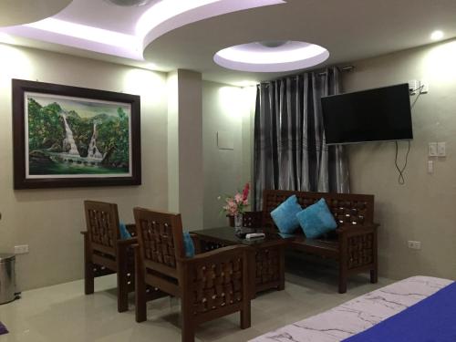 ein Wohnzimmer mit einem Tisch und Stühlen sowie einem TV in der Unterkunft EA Apartelle - Metro Vigan in Vigan City
