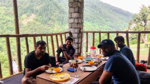 a group of men sitting around a table eating food at Ara Camps in McLeod Ganj