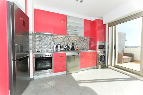 a red kitchen with stainless steel appliances and red cabinets at Exclusive Luxury Apartments in Oceano Atlantico Complex in Portimão