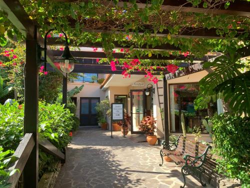 a bench under a pergola with flowers and plants at Vila Ventura Village in Caniço