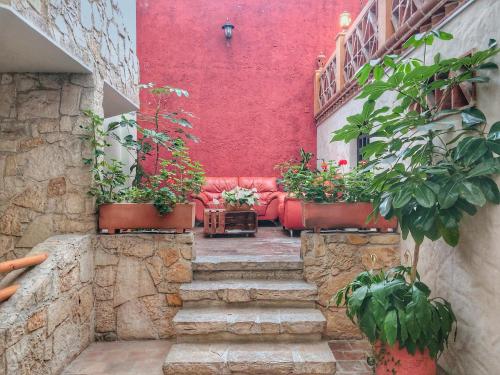a red wall with stairs and potted plants at Plaza Magnolias Suites in San Cristóbal de Las Casas