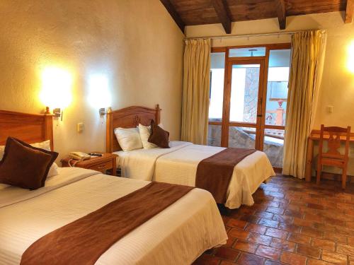 a hotel room with two beds and a window at Plaza Magnolias Suites in San Cristóbal de Las Casas