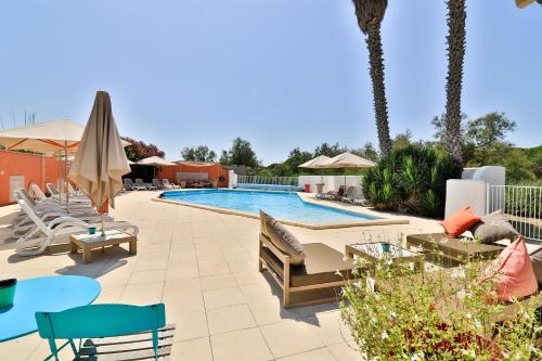 une piscine dans un complexe hôtelier avec chaises et parasols dans l'établissement Les Rizières, à Saintes-Maries-de-la-Mer
