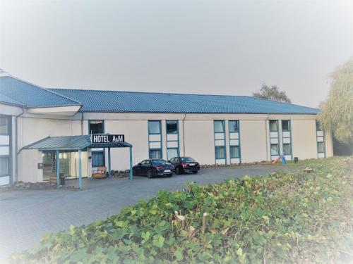 a hotel inn with two cars parked in front of it at A&M Hotel Barsinghausen in Bad Nenndorf