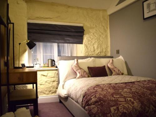 a bedroom with a bed and a desk and a window at The Mendip Inn in Binegar