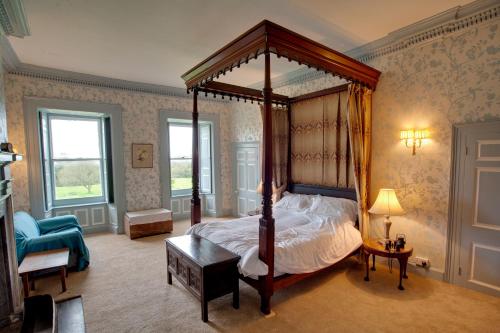 a bedroom with a canopy bed and a blue chair at Kelly House Country B&B in Lifton