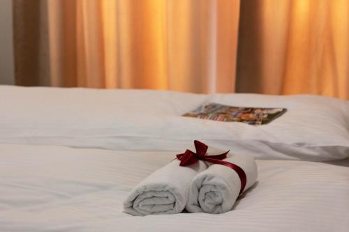 a white towel with a red ribbon on a bed at Ares ApartHotel in Cluj-Napoca