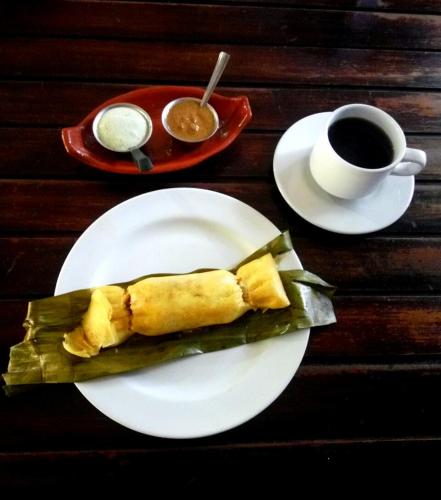 a plate with a piece of food and a cup of coffee at Hostal Nova Colonial in Puerto Colombia