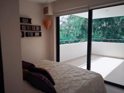 1 dormitorio con cama y ventana grande en Beachside Resplandor Maya Corasol with balcony for 4 people, en Playa del Carmen