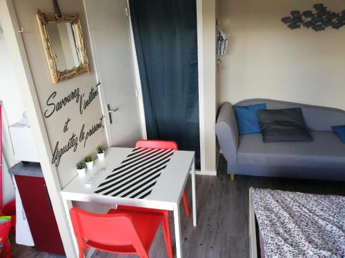 Cette petite chambre comprend une table, des chaises et un canapé. dans l'établissement Charmant studio bord de mer, à Ouistreham