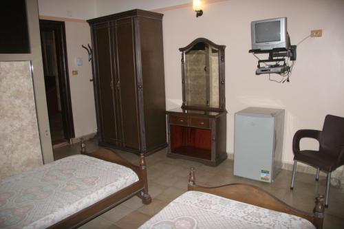 Habitación con cama, armario y TV. en Fouad Hotel, en Alejandría