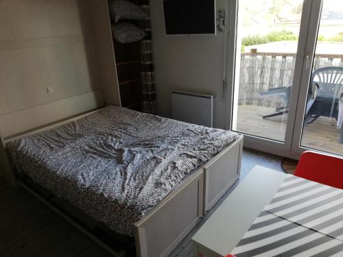 une chambre avec un lit et une porte coulissante en verre dans l'établissement Charmant studio bord de mer, à Ouistreham