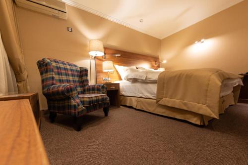 a hotel room with a bed and a chair at Daria Suite in Târgu Jiu