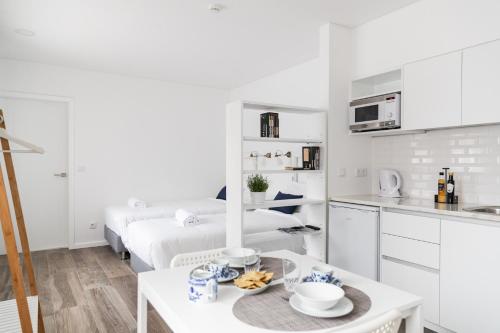 a white kitchen with a table and a bed at Botica Guesthouse in Espinho