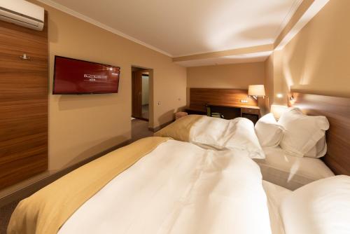 a hotel room with two beds and a tv on the wall at Daria Suite in Târgu Jiu