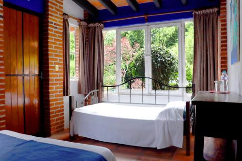 a bedroom with two beds and a large window at Hotel La Posada del Valle in Tepoztlán