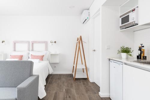 a white apartment with a bed and a kitchen at Botica Guesthouse in Espinho