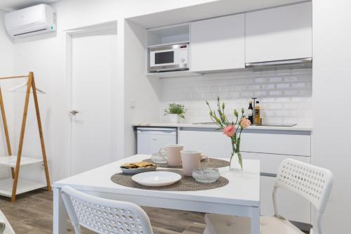 a white kitchen with a table and chairs at Botica Guesthouse in Espinho