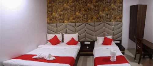 two beds in a room with red and white pillows at Hotel Apple Inn in Navi Mumbai