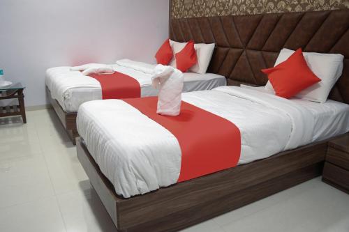 two beds in a room with red and white sheets at Hotel Apple Inn in Navi Mumbai