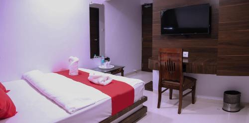 a bedroom with a bed and a desk and a television at Hotel Apple Inn in Navi Mumbai
