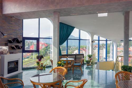 a living room with tables and chairs and windows at Hotel Ski&Sky in Predeal