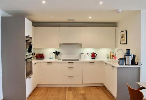 a kitchen with white cabinets and a wooden floor at Endcliffe in Falmouth