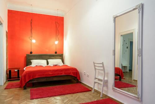 リヴィウにあるRed & Yellow Apartmentの赤い壁のベッドルーム1室、鏡付きのベッド1台が備わります。