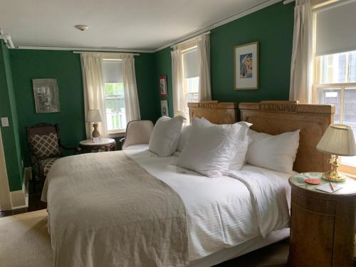 a bedroom with green walls and a bed with white pillows at Bridgehampton Inn in Bridgehampton
