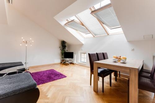 ein Wohnzimmer mit einem Tisch, Stühlen und Oberlichtern in der Unterkunft JT's Apartments Bílkova str. in Prag