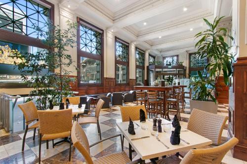 a restaurant with tables and chairs and windows at Batman's Hill on Collins in Melbourne