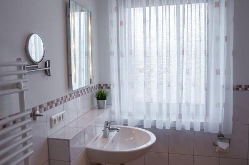 a white bathroom with a sink and a window at Haus-Meeresglueck-Wohnung-Seeloewe in Dahme