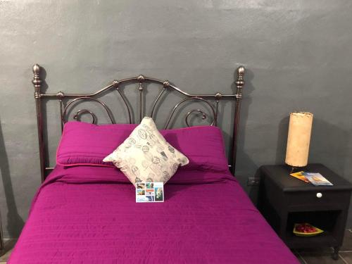 a bed with purple sheets and pillows on it at Estancia del Sol in Cabo San Lucas