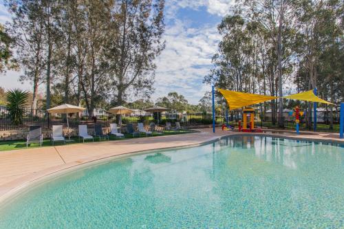 a swimming pool at a resort with a playground at BIG4 Karuah Jetty Holiday Park in Karuah